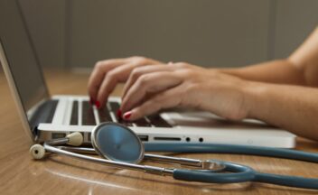 Zorgprofessional werkt met laptop en stethoscoop aan data-analyse